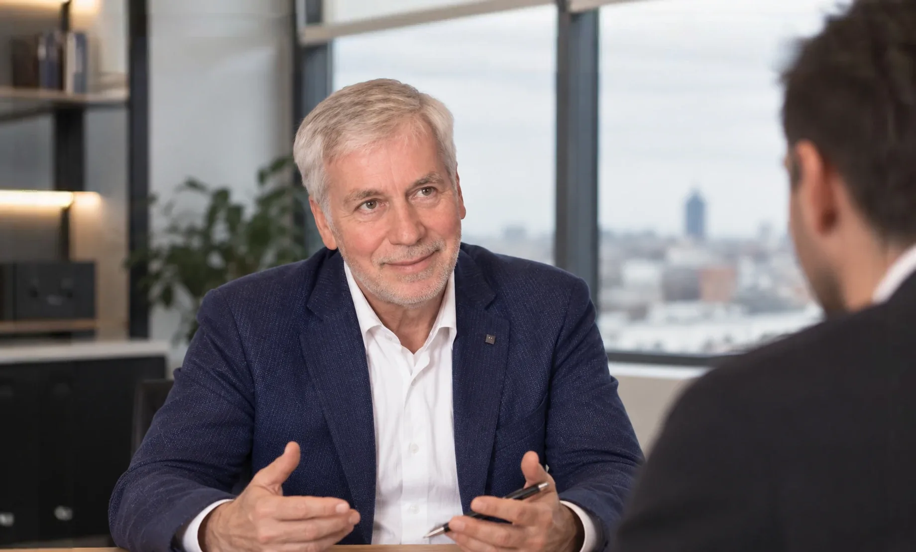 Werner Fürstenberg im Gespräch an einem Besprechungstisch, einem Gegenüber zugewandt